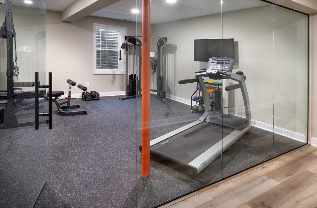 A renovated fitness room with floor to ceiling glass windows and equipment throughout.