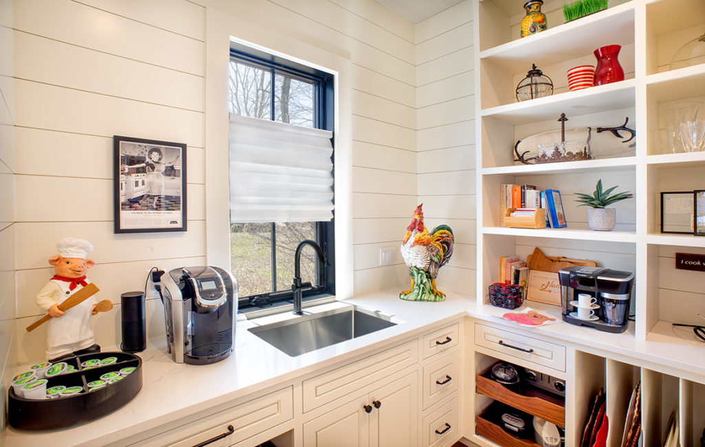 Scullery with a sink, window, shelving. and rooster decorations.