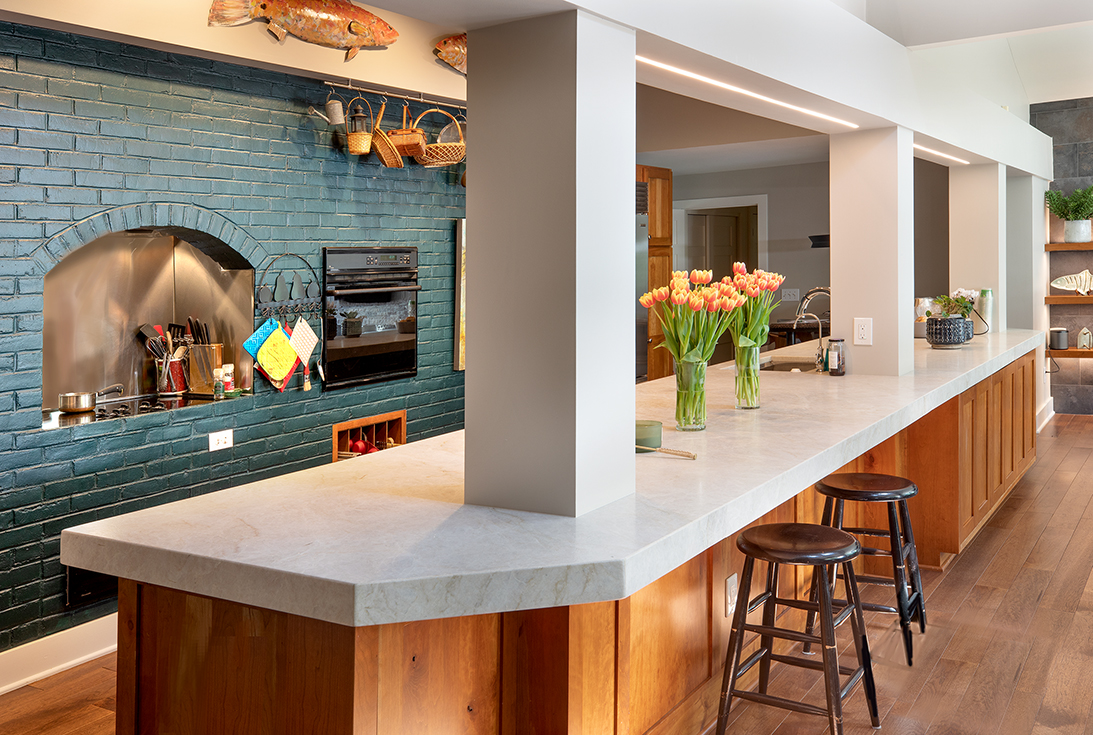An elevated, renovated kitchen island by Epic Group Ohio complete with a painted blue brick wall with a built in stovetop and oven.