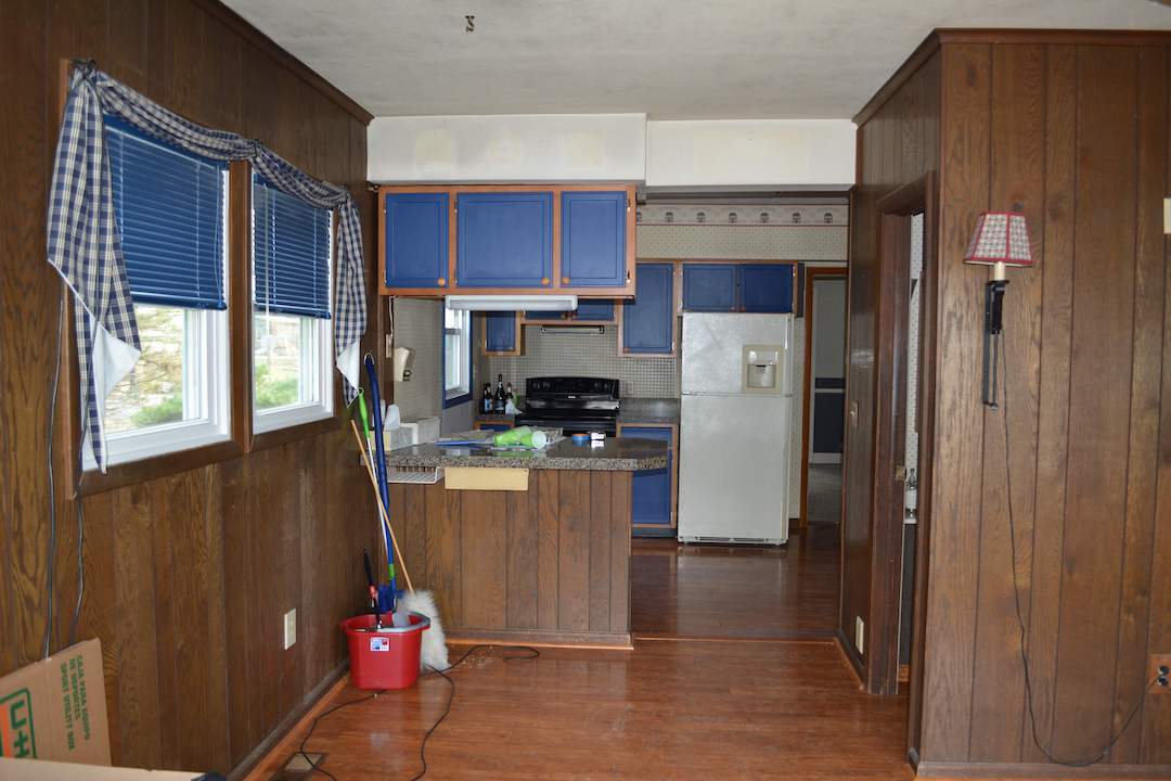 An outdated kitchen interior with dated brown cabinetry with royal blue accents before renovation.