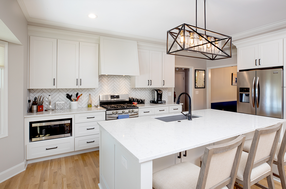 A modern, updated kitchen after an Epic renovation with shiny, white countertops and a large island.